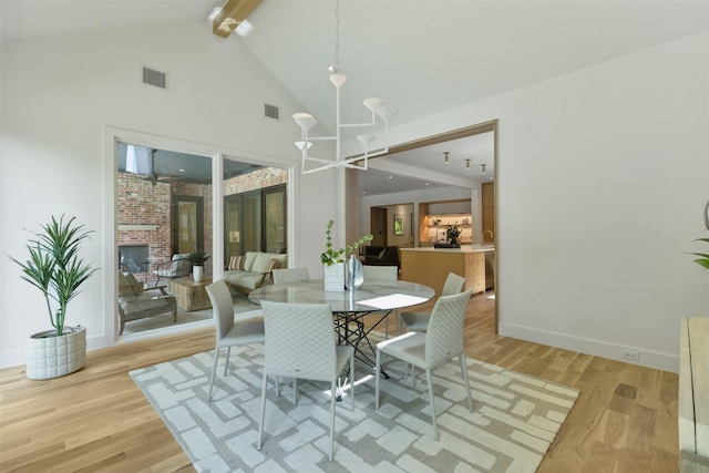 dining area with light wood-type flooring, beam ceiling, and visible vents
