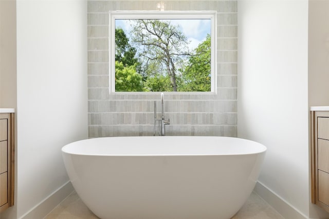 bathroom featuring baseboards, a soaking tub, and vanity