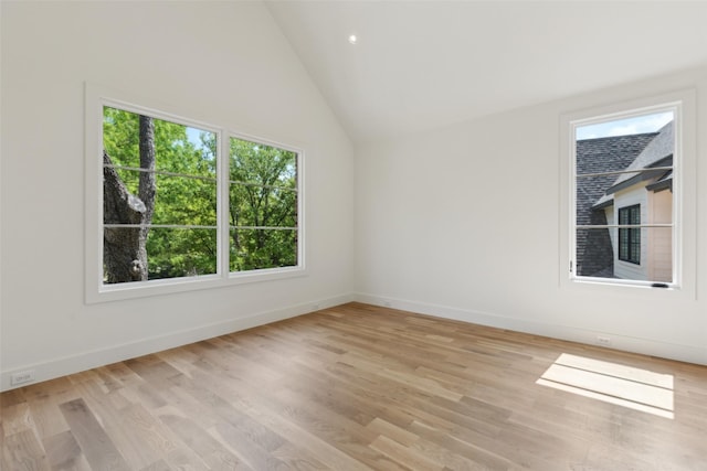 unfurnished room featuring baseboards, vaulted ceiling, and light wood finished floors