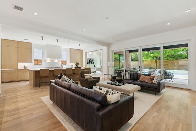 living area featuring recessed lighting, light wood finished floors, and visible vents