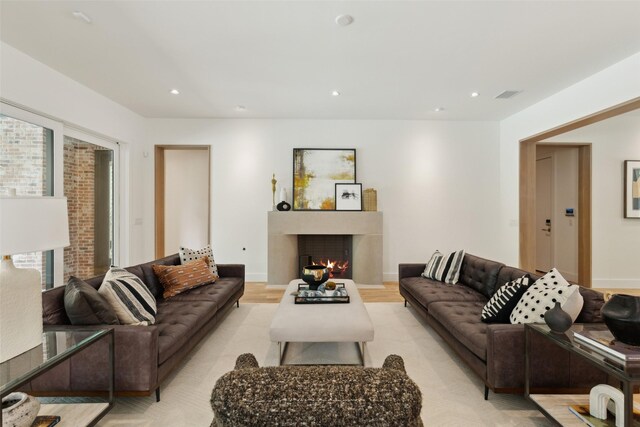 7114 Pasadena Ave, Dallas, TX 75214 - living room featuring recessed lighting, light wood-style floors, a warm lit fireplace, and visible vents