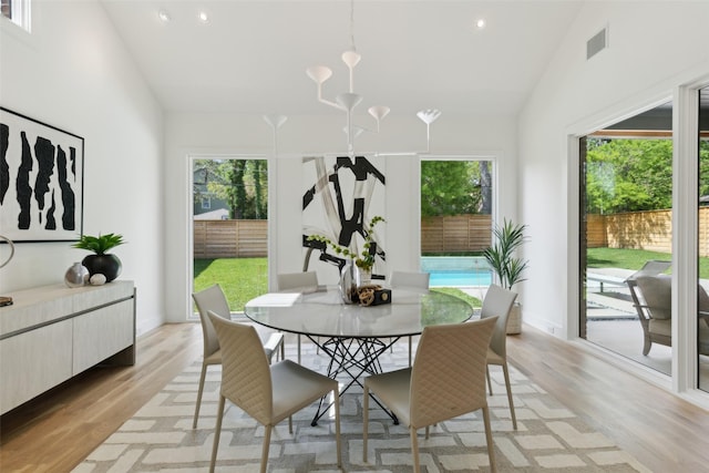 dining area featuring high vaulted ceiling, a wealth of natural light, and light wood-style floors