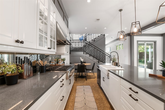 kitchen featuring white cabinetry, recessed lighting, a sink, pendant lighting, and glass insert cabinets