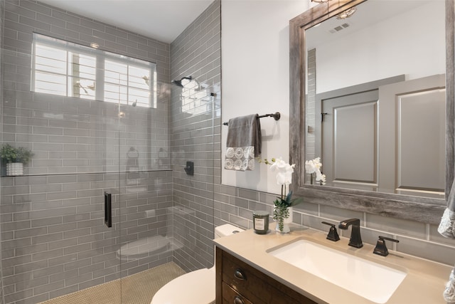 bathroom with a stall shower, toilet, vanity, visible vents, and decorative backsplash
