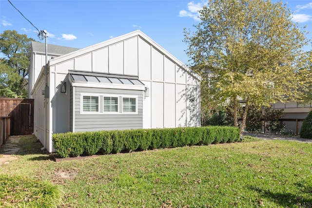 view of side of home featuring metal roof, fence, a standing seam roof, board and batten siding, and a yard