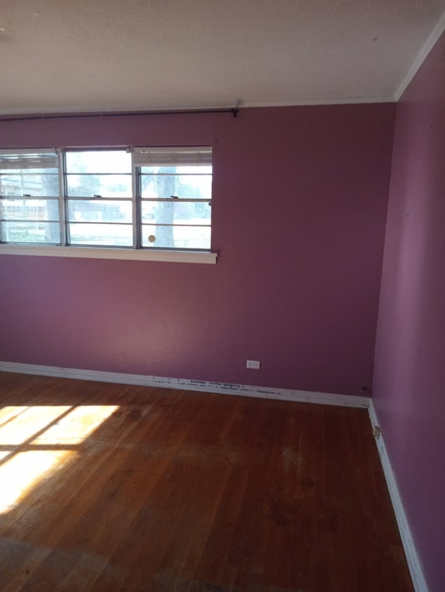 spare room with baseboards and wood finished floors
