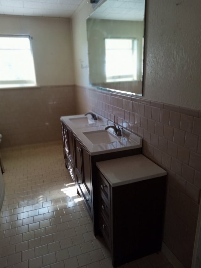 bathroom with a wainscoted wall, a sink, and plenty of natural light