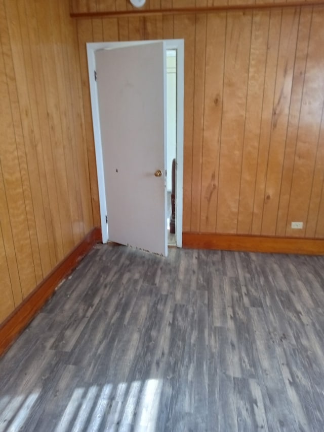 spare room with baseboards, wood finished floors, and wood walls
