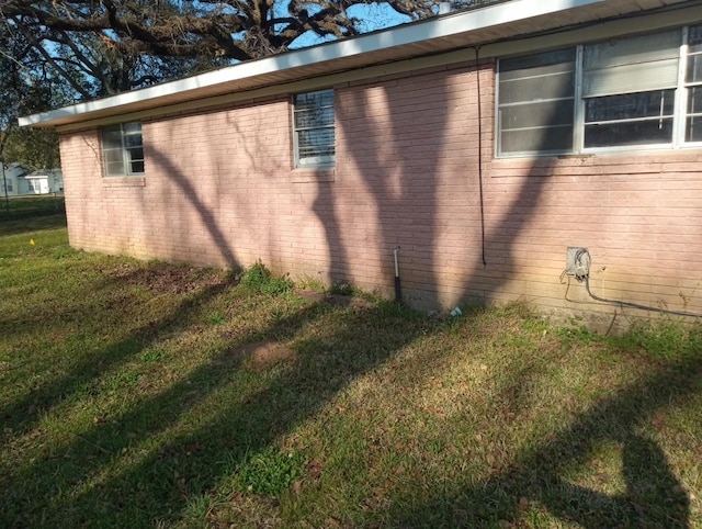 view of side of property featuring brick siding and a yard
