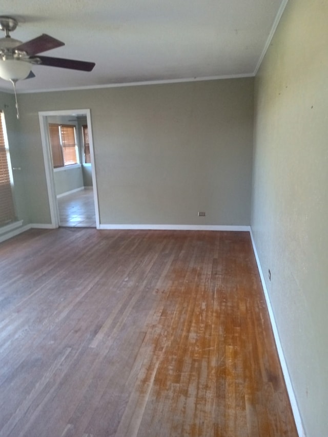 spare room with crown molding, baseboards, ceiling fan, and wood finished floors