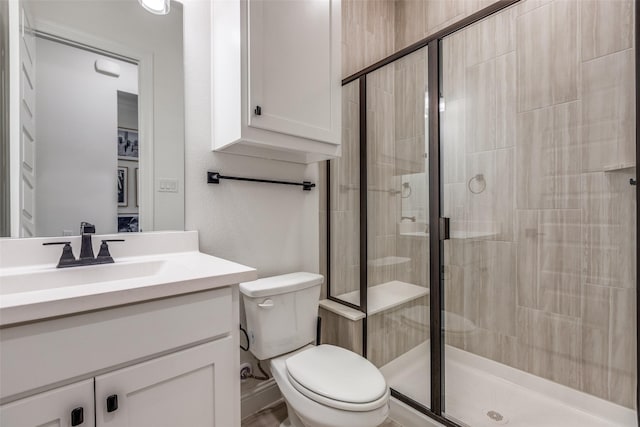 bathroom with a stall shower, toilet, and vanity