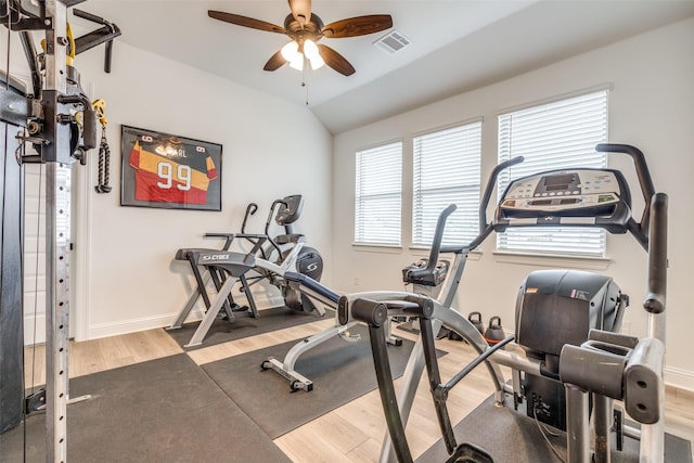exercise room with lofted ceiling, baseboards, visible vents, a ceiling fan, and wood finished floors