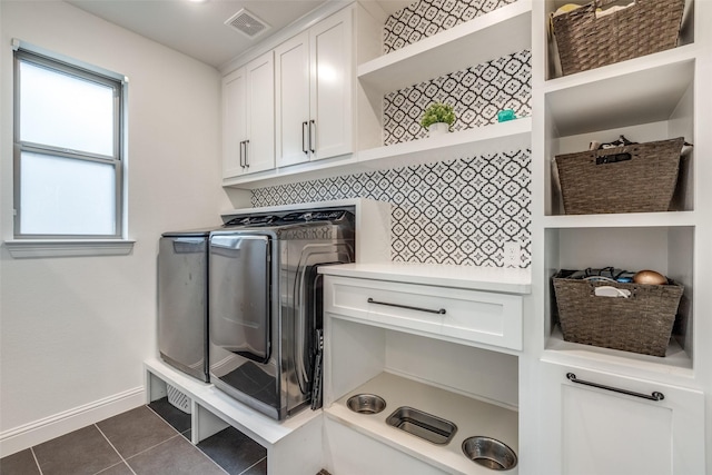 laundry room with visible vents, dark tile patterned floors, baseboards, cabinet space, and washing machine and dryer