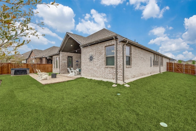back of house with a fenced backyard, brick siding, a yard, and a patio