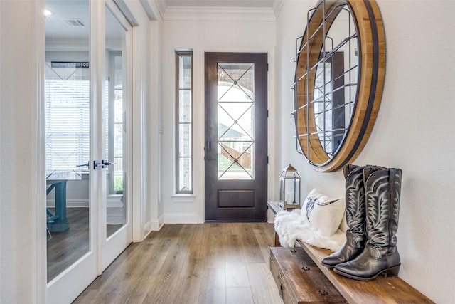 foyer featuring wood finished floors, crown molding, and plenty of natural light
