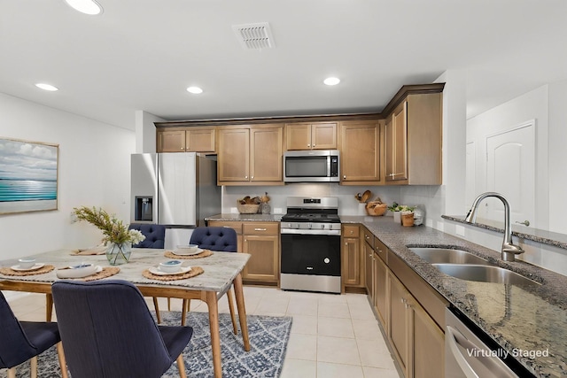 1256 Bright Stars Dr, Little Elm, TX 76227 - kitchen featuring stainless steel appliances, a sink, dark stone countertops, light tile patterned floors, and recessed lighting