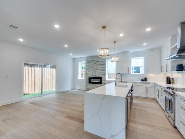 kitchen with high end stainless steel range, decorative backsplash, visible vents, a high end fireplace, and light stone countertops