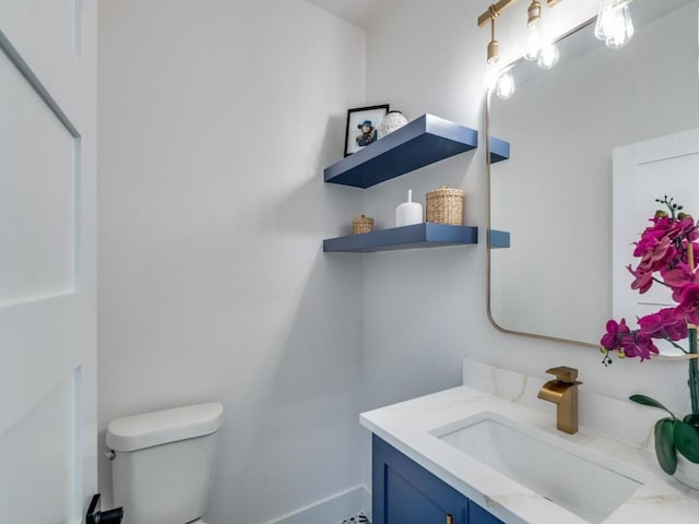 half bath featuring toilet, vanity, and baseboards