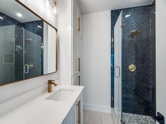 bathroom featuring a shower stall, baseboards, and vanity