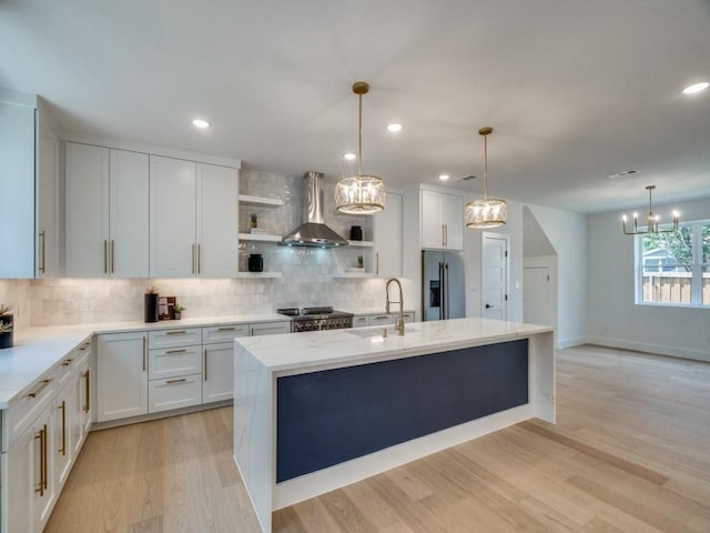 kitchen featuring open shelves, stainless steel fridge with ice dispenser, wall chimney exhaust hood, stove, and an inviting chandelier