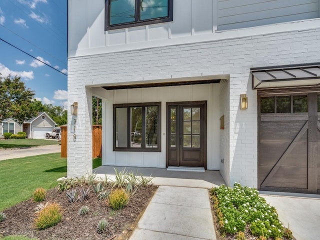 entrance to property featuring board and batten siding, brick siding, and a lawn