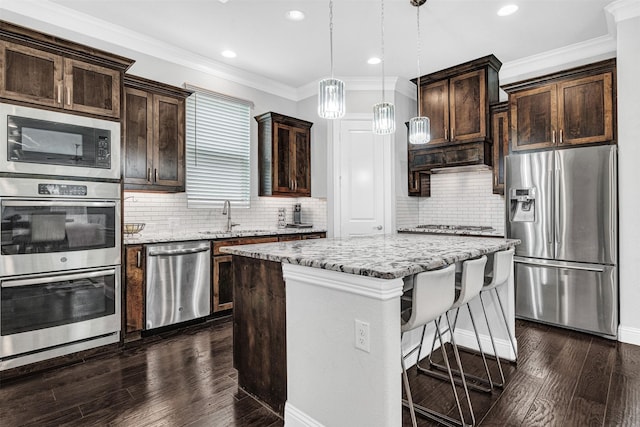 3627 Harvest Ln, Frisco, TX 75034 - kitchen with appliances with stainless steel finishes, dark brown cabinets, light stone counters, a kitchen island, and recessed lighting