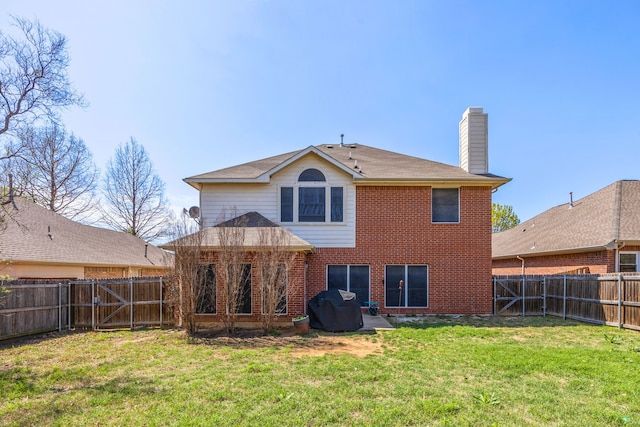 back of property with brick siding, a yard, a chimney, and a fenced backyard