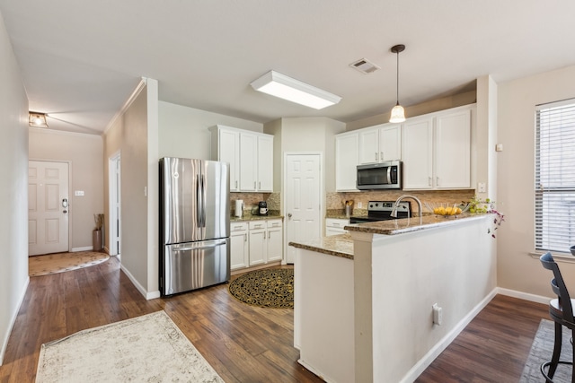 kitchen with visible vents, a peninsula, stainless steel appliances, white cabinetry, and light stone counters