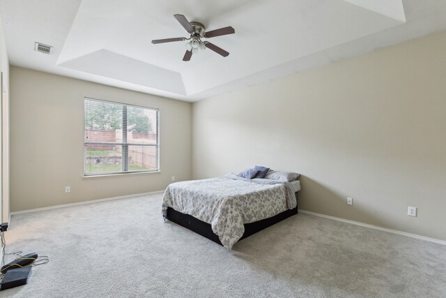 bedroom featuring carpet flooring, visible vents, baseboards, ceiling fan, and a tray ceiling