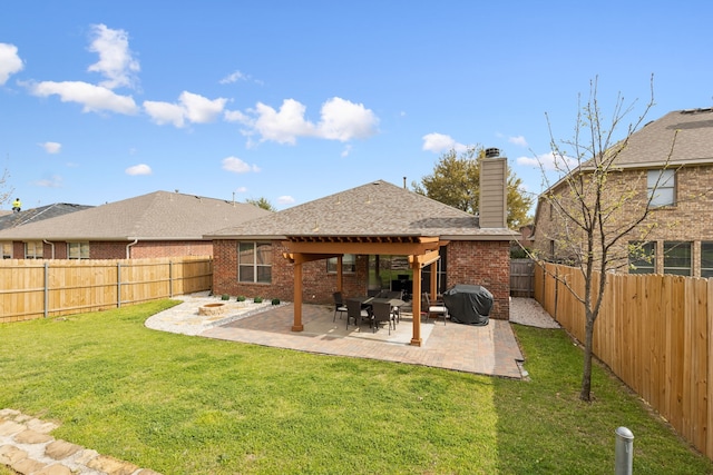 back of property featuring a fenced backyard, a patio area, brick siding, a yard, and a chimney