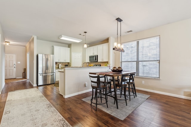 dining space featuring baseboards, visible vents, an inviting chandelier, and dark wood finished floors