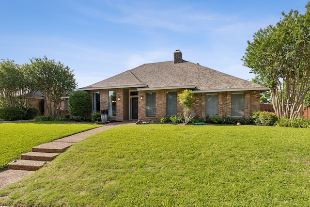 view of front facade with brick siding, a front lawn, roof with shingles, and a chimney
