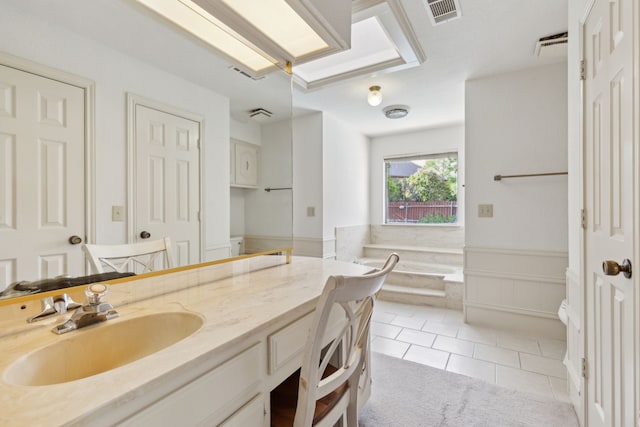 full bathroom with vanity, tile patterned flooring, a garden tub, and a wainscoted wall
