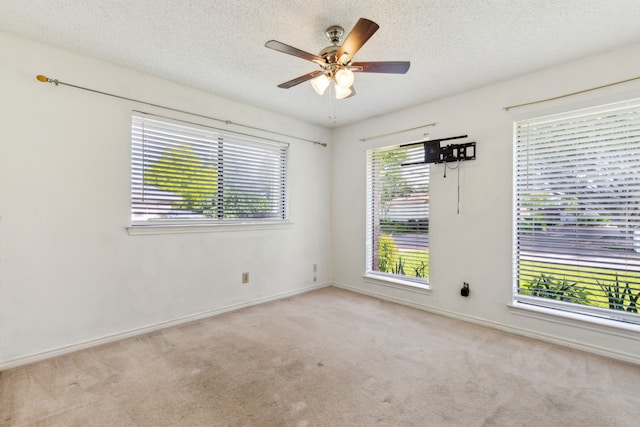 spare room with carpet flooring, a ceiling fan, a textured ceiling, and baseboards