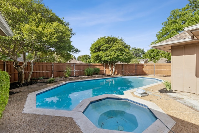 view of pool featuring a fenced backyard and a pool with connected hot tub