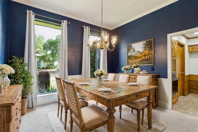 dining room with a chandelier, light colored carpet, healthy amount of natural light, ornamental molding, and wainscoting