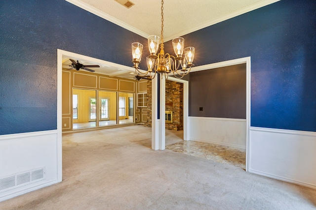 unfurnished dining area featuring a chandelier, ornamental molding, carpet floors, ceiling fan, and a wainscoted wall