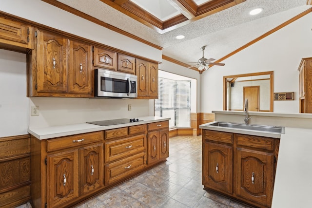 kitchen with stainless steel microwave, a sink, brown cabinets, ornamental molding, and light countertops