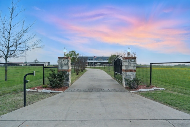 gate at dusk with a lawn and a fenced front yard