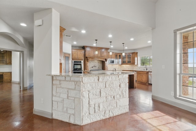 kitchen featuring tasteful backsplash, stainless steel appliances, visible vents, brown cabinetry, and glass insert cabinets