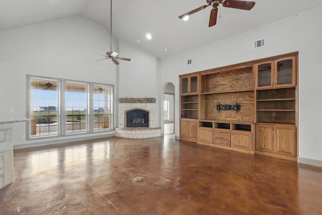 unfurnished living room with finished concrete flooring, arched walkways, visible vents, a brick fireplace, and ceiling fan