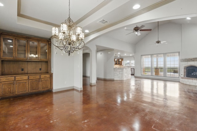 unfurnished living room with ceiling fan with notable chandelier, a raised ceiling, arched walkways, visible vents, and a brick fireplace