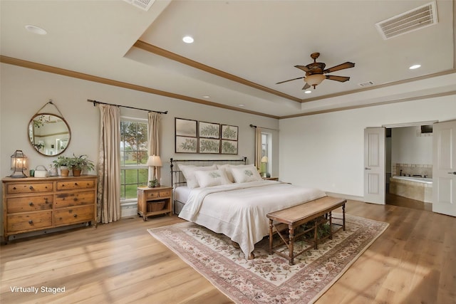 bedroom featuring a tray ceiling, visible vents, and light wood-type flooring