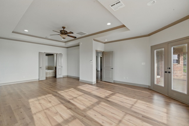 unfurnished room featuring french doors, a raised ceiling, light wood-style flooring, and visible vents