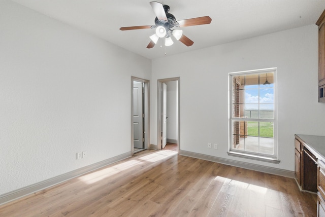interior space with light wood-style flooring, baseboards, and ceiling fan