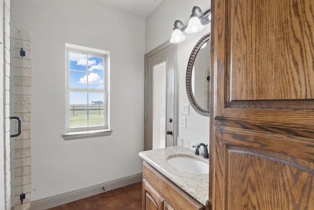 full bathroom featuring baseboards, a shower with shower door, and vanity