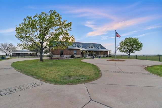 view of front of property with a front yard, fence, stone siding, and curved driveway