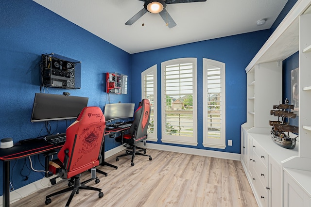 office space with baseboards, a ceiling fan, and light wood finished floors