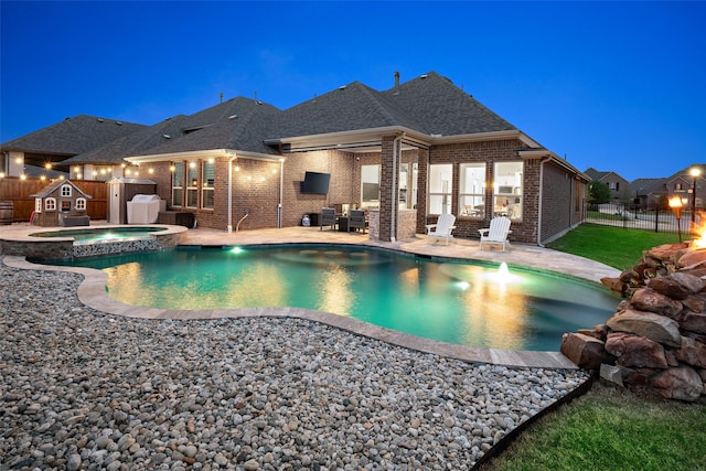 view of swimming pool with fence, a patio, and a pool with connected hot tub