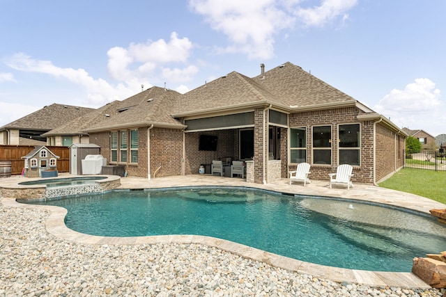 view of swimming pool featuring a storage shed, a pool with connected hot tub, an outbuilding, a fenced backyard, and a patio